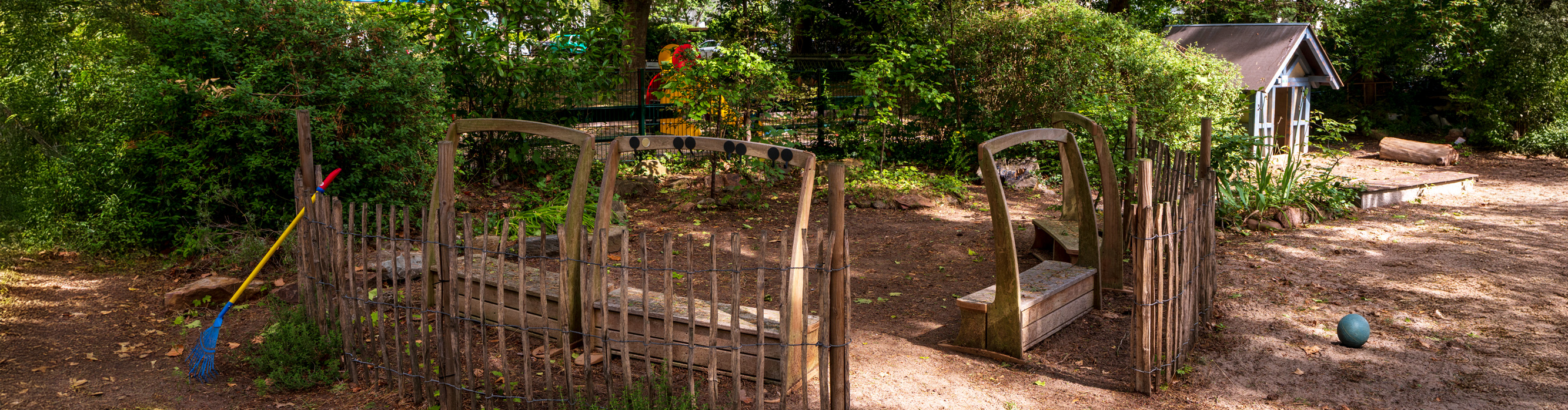 Aussengelände und Spielplatz des Melanchthonkindergartens mit Holzbank und Spielehäuschen